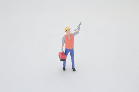 A miniature worker figure in a safety helmet and tool vest standsの写真素材