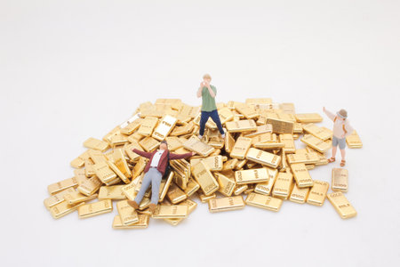 A creative concept depicting toy figures amidst a pile of gold barsの写真素材