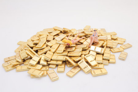 Two miniature figures reclining on a pile of gold barsの写真素材