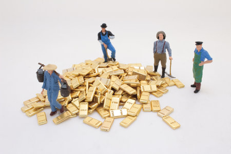 worker figurines standing around a stack of gold barsの写真素材