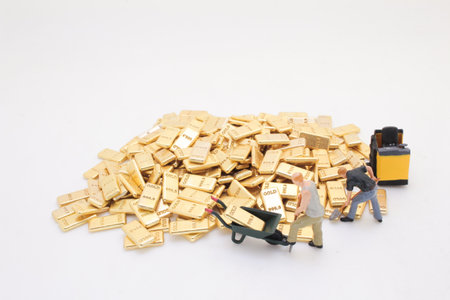 Three miniature figures are moving gold bars using toolsの写真素材