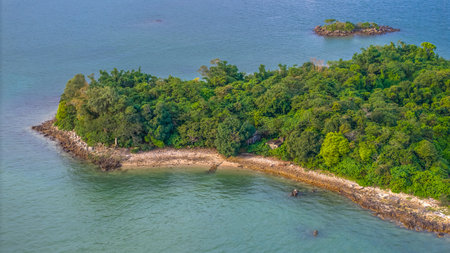 green tropical island surrounded by tranquil blue ocean waterの写真素材