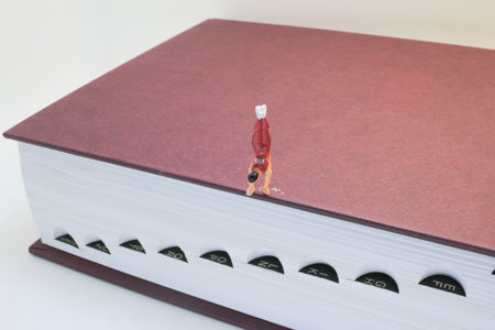 A detailed close-up showing a miniature figurine ascending the pages