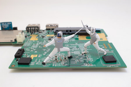 Two small-scale fencing figures are staged on a green circuit board