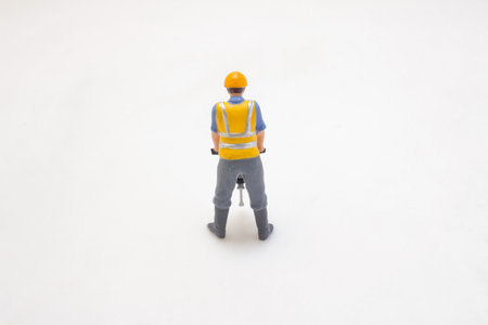 A miniature construction worker figure stands focused, operating