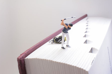 A creative setup featuring a tiny figurine cleaning a large bookの写真素材