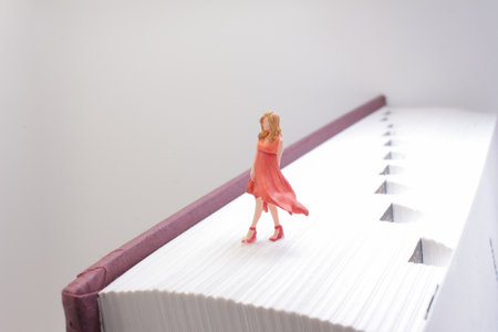Miniature figurine of a woman in a red dress stands on the pages of a bookの写真素材
