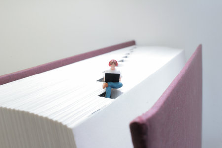creative concept of a small figure sitting with a laptop on a big bookの写真素材