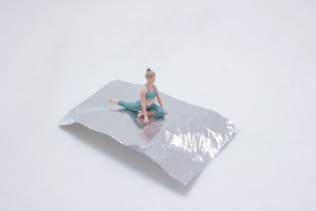 An artistic depiction of a tiny figure performing a yoga pose on reflective metallicの写真素材