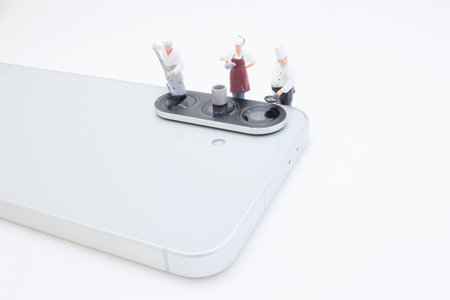 miniature chef figurines stand on the camera module of a modern