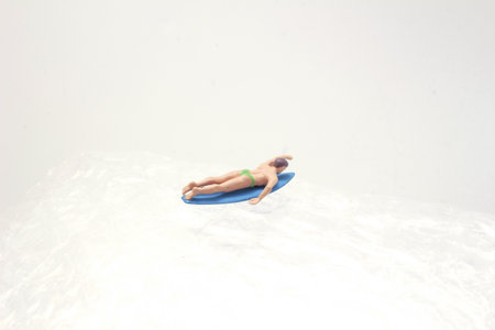 A small plastic surfer figurine, wearing purple shorts
