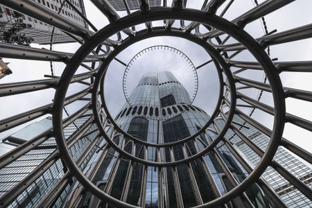 A towering glass skyscraper rises behind a dramatic stainless spiralのeditorial素材
