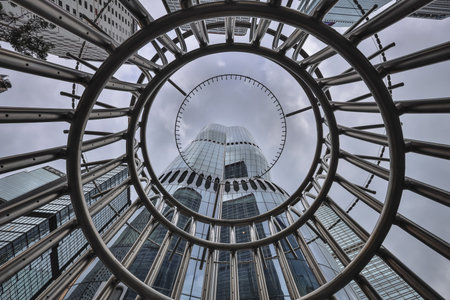 A towering glass skyscraper rises behind a dramatic stainless spiralのeditorial素材