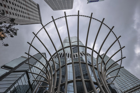 A towering glass skyscraper rises behind a dramatic stainless spiral
