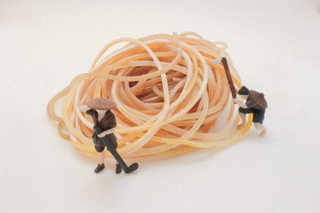 Two miniature figures in simple outfits push a tangled ballの写真素材