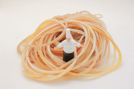 A small chef figurine sits amid a tangle of orange rubber bands,