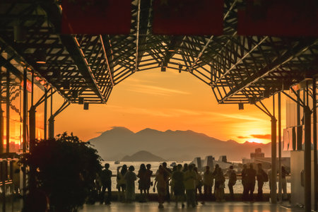 Golden sunset lights a glass walkway where groups stand and walk