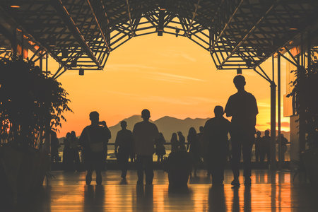 Golden sunset lights a glass walkway where groups stand and walkのeditorial素材