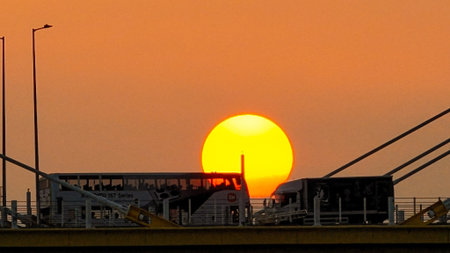 A warm sunset behind a cable-stayed bridge creates striking silhouettes