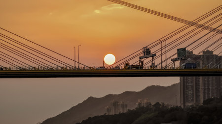 Bridge silhouettes frame a glowing sunset over calm water, wの写真素材