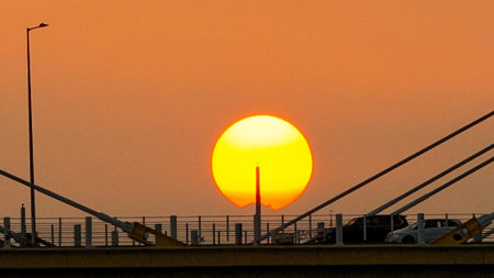 A warm sunset behind a cable-stayed bridge creates striking silhouettesの写真素材