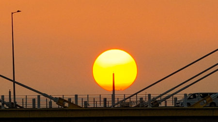 A warm sunset behind a cable-stayed bridge creates striking silhouettesの写真素材