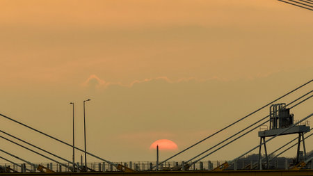 A warm sunset behind a cable-stayed bridge creates striking silhouettesの写真素材