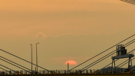 A warm sunset behind a cable-stayed bridge creates striking silhouettesの写真素材