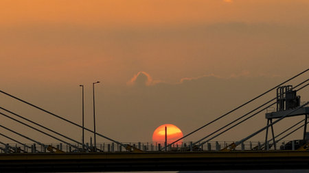 A warm sunset behind a cable-stayed bridge creates striking silhouettesの写真素材