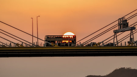 A dramatic sunset casts warm orange light over a city bridgeの写真素材