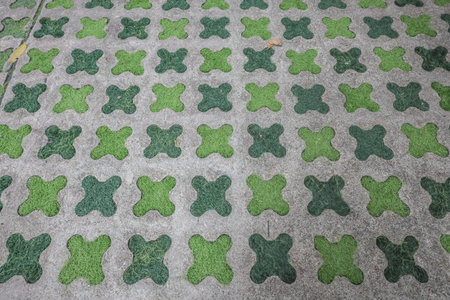 grid of green, X-shaped grass pavers set on a gray concrete surface