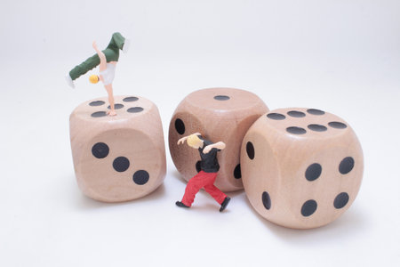 Tiny painted figures balance and move atop oversized wooden dice,の写真素材
