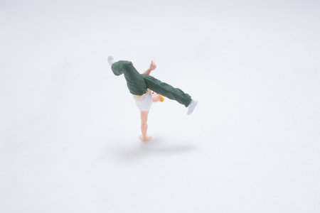 A miniature toy figure performs a handstand on a clean white surfaceの写真素材