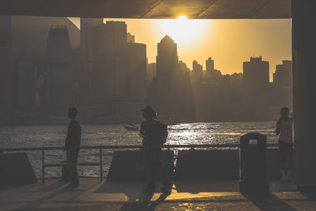 Silhouettes of visitors stand against a golden sunset as a dense city skyline Nov 16 2025のeditorial素材