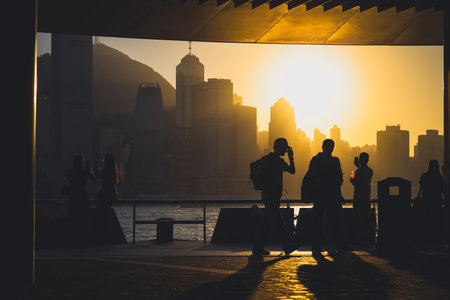 figures stand by a glass railing as a brilliant orange sunset Nov 16 2025のeditorial素材
