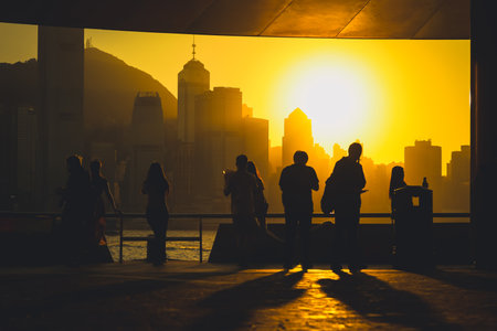 Silhouetted figures stand on a balcony as a warm sunset bathes Nov 16 2025のeditorial素材