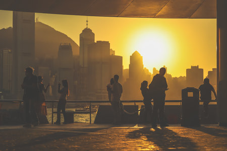 Silhouettes of visitors stand against a golden sunset as a dense city skyline Nov 16 2025のeditorial素材