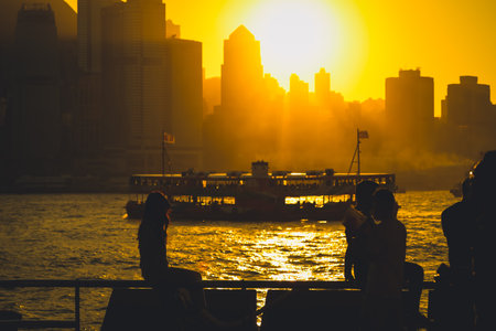 Two silhouetted figures by a railing overlook a golden sunset Nov 16 2025のeditorial素材