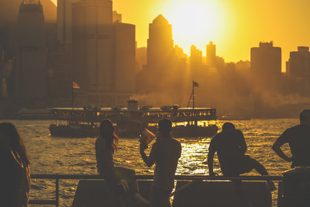 Two silhouetted figures by a railing overlook a golden sunset Nov 16 2025のeditorial素材