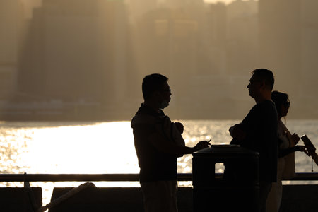 stand by the water at golden hour, with a distant city skyline Nov 16 2025のeditorial素材