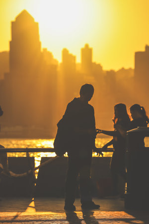 Silhouettes of visitors stand against a golden sunset as a dense city skyline Nov 16 2025のeditorial素材