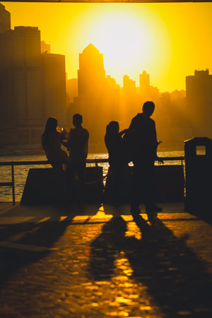Silhouettes of visitors stand against a golden sunset as a dense city skyline Nov 16 2025のeditorial素材