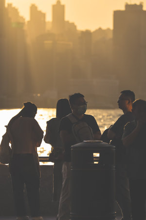 stand by the water at golden hour, with a distant city skyline Nov 16 2025のeditorial素材