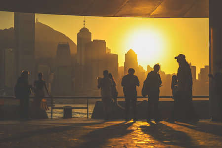 Silhouetted figures stand on a balcony as a warm sunset bathes Nov 16 2025のeditorial素材