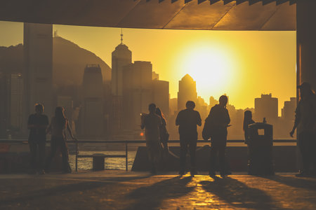 Silhouetted figures stand on a balcony as a warm sunset bathes Nov 16 2025のeditorial素材