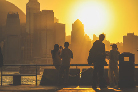 Silhouetted figures stand on a balcony as a warm sunset bathes Nov 16 2025のeditorial素材