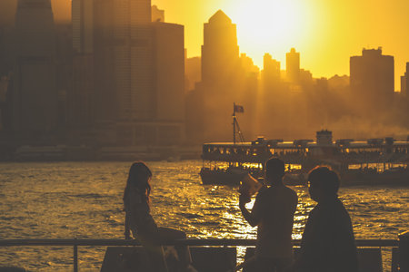 Two silhouetted figures by a railing overlook a golden sunset Nov 16 2025のeditorial素材
