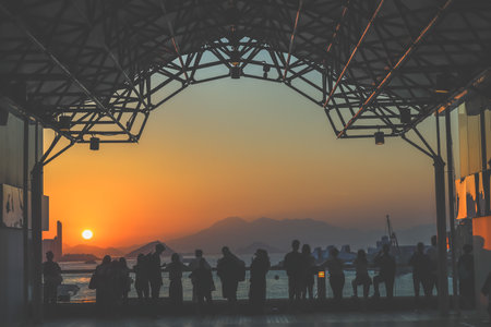 Silhouetted visitors line a waterfront promenade as the sun sets Nov 16 2025のeditorial素材