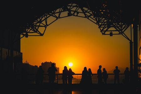 Silhouetted visitors line a waterfront promenade as the sun sets Nov 16 2025のeditorial素材