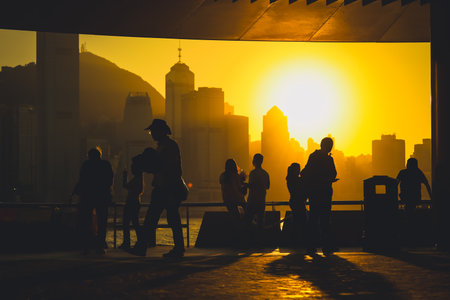 Silhouetted figures stand on a balcony as a warm sunset bathes Nov 16 2025のeditorial素材